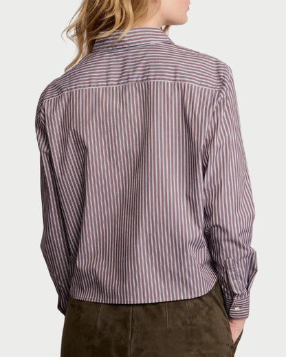 Woman wearing a striped shirt and dark pants on a plain background