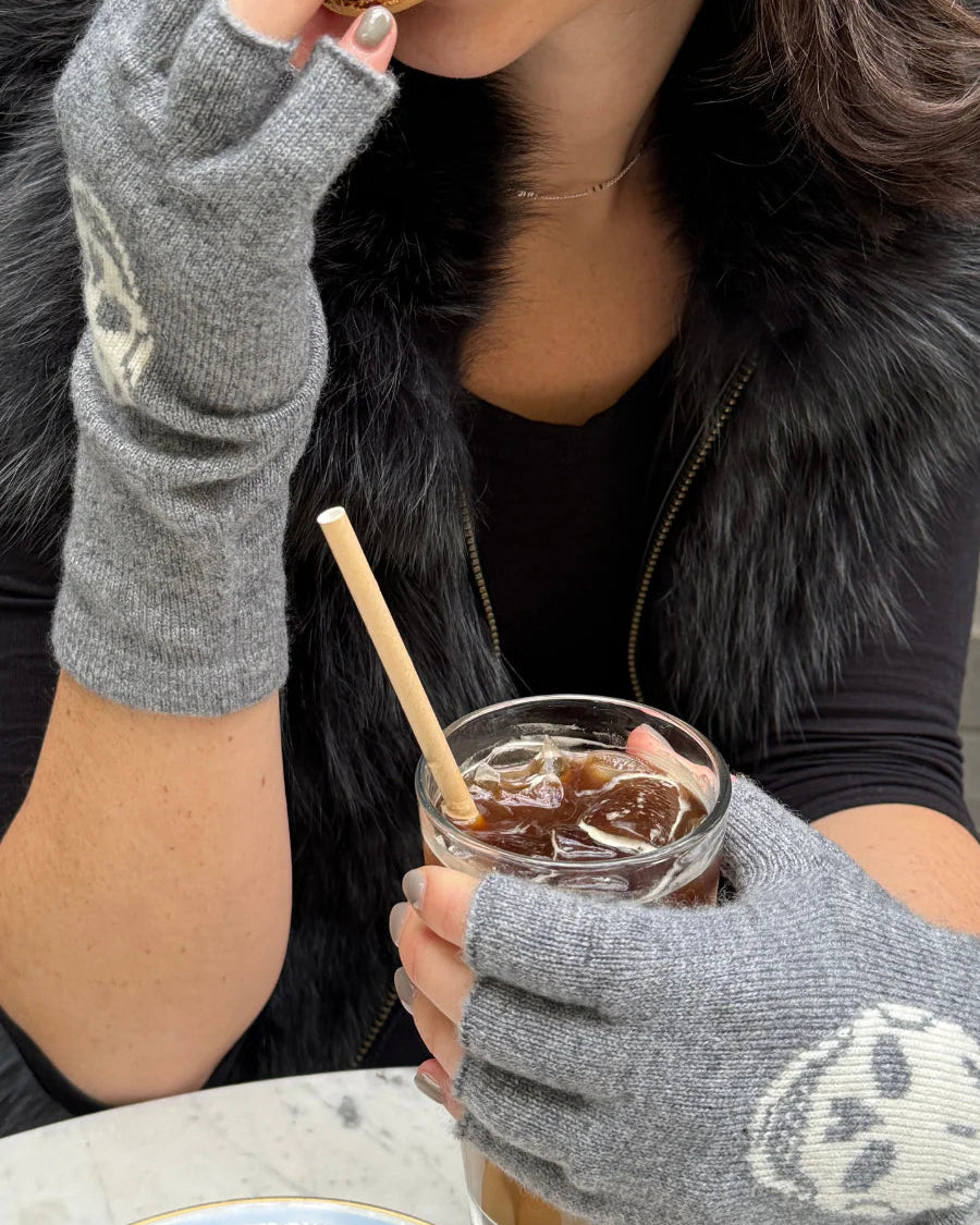 Person eating a macaron and holding a drink with a straw outdoors