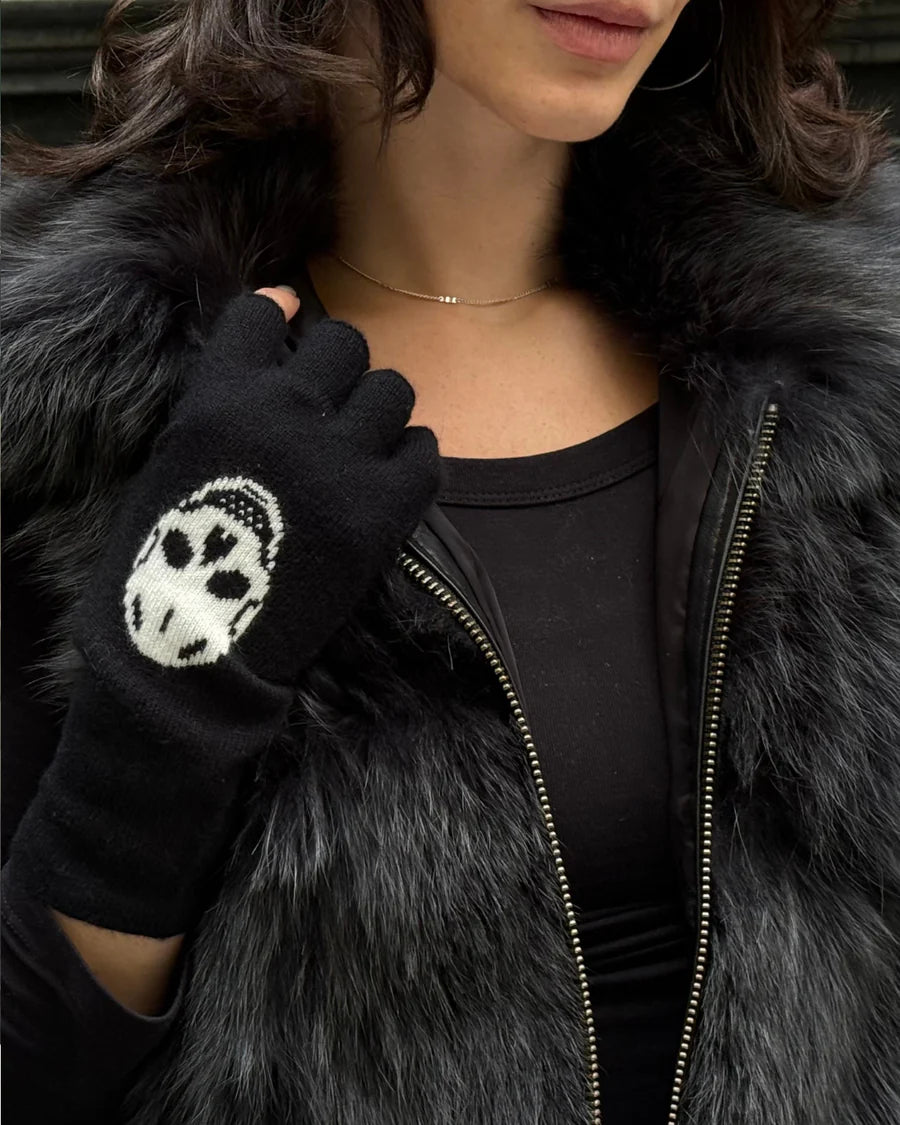Person wearing a black paw print glove with a fur-lined coat