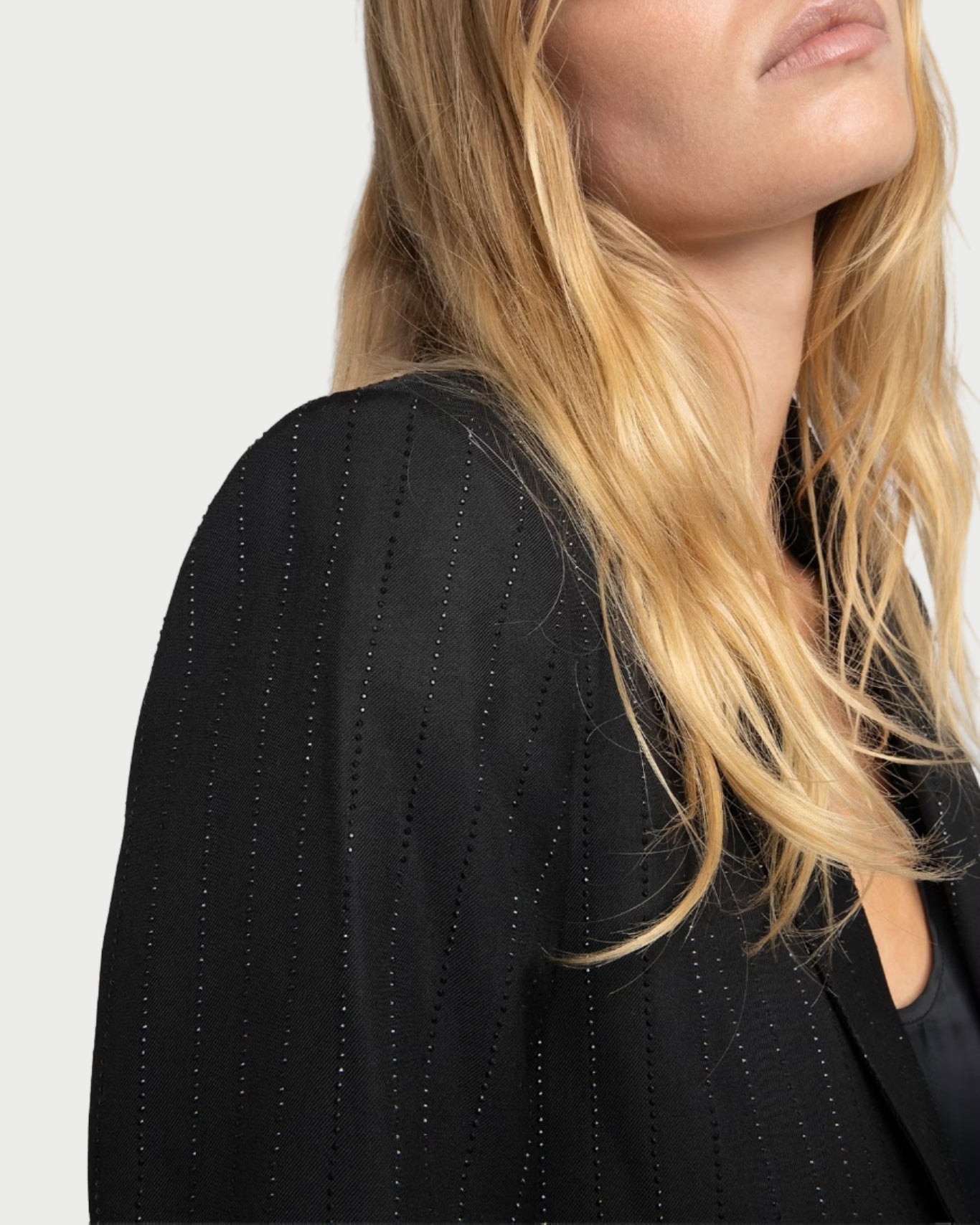 Person wearing a black blazer with a plain background