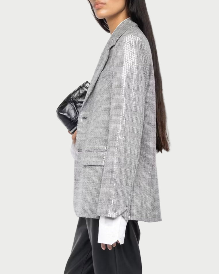 Woman wearing a gray checkered blazer and black pants on a white background