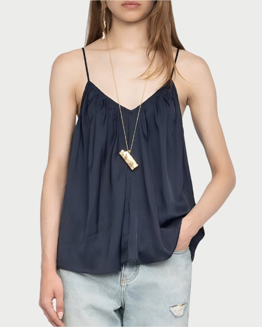 Woman wearing a dark blue sleeveless top and light blue jeans on a white background