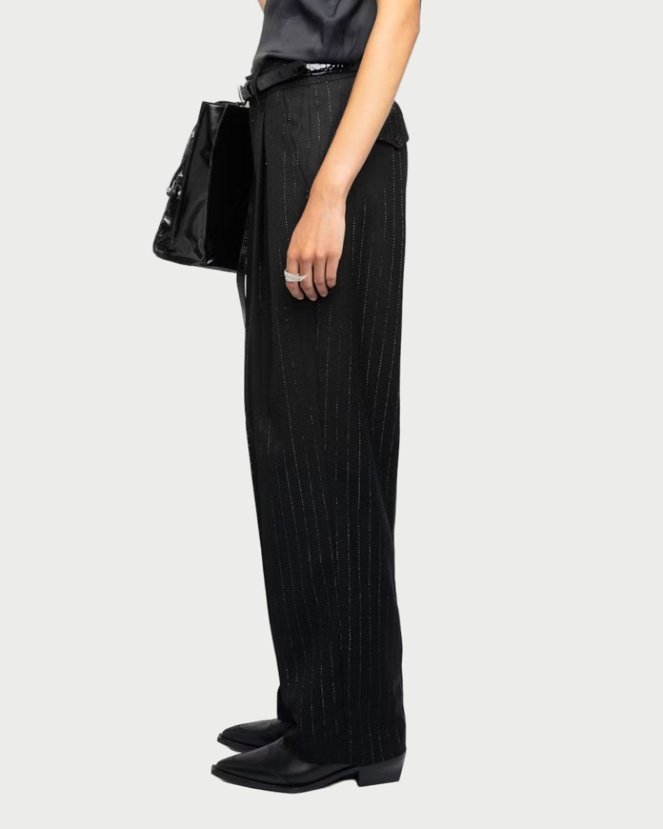 Woman wearing a black sleeveless top and black pants against a white background