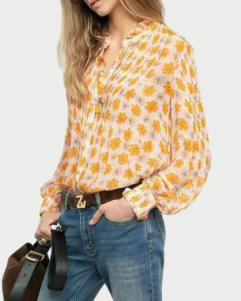 Woman wearing a patterned blouse and jeans, holding a handbag on a white background