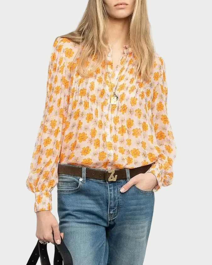 Woman wearing a yellow floral blouse and blue jeans, holding a brown handbag on a white background