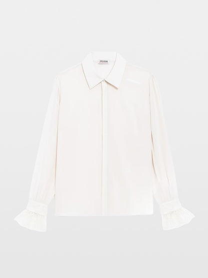A long-sleeve white button-up blouse with a pointed collar and ruffled cuffs, displayed flat against a light gray background.