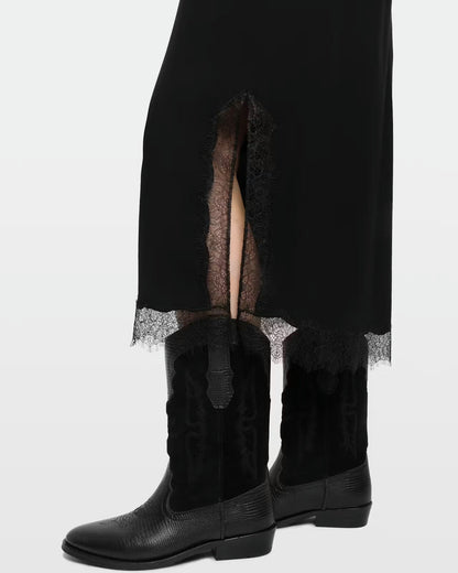 Black lace skirt with a side slit, paired with black leather cowboy boots, photographed against a light gray studio background.
