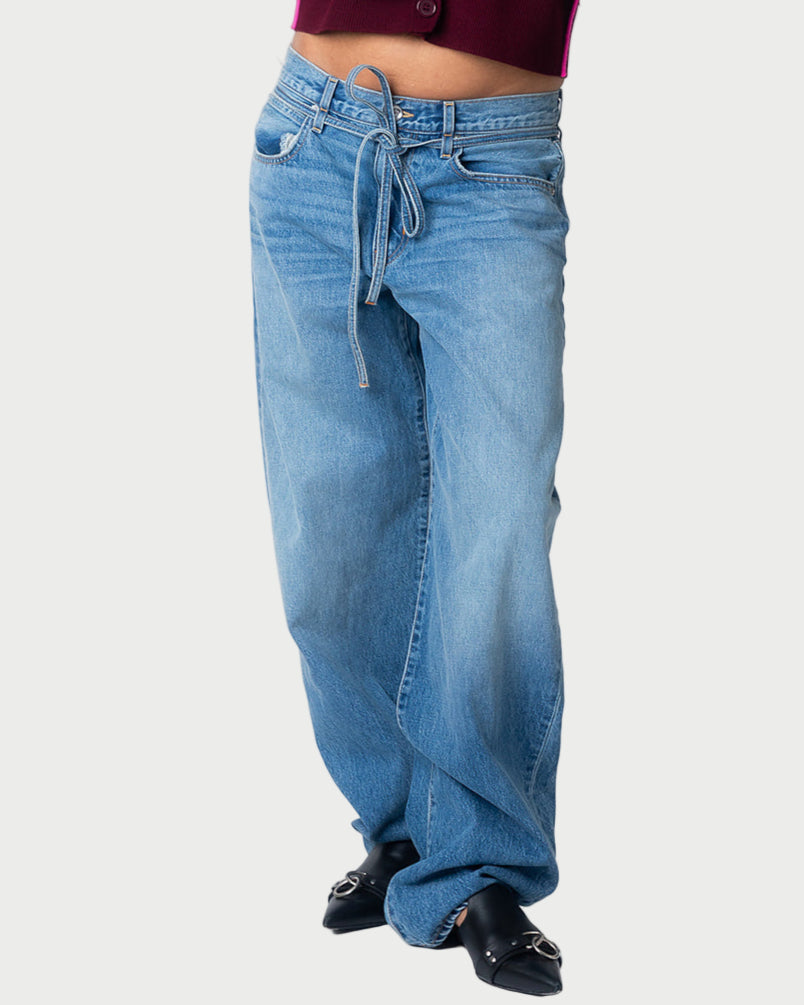 Model wears SLVRLAKE Hailey Belted Curve Jean—light blue, high-rise fit with drawstring waist, crafted from premium cotton denim. Styled with black open-toe heels and a cropped burgundy top. Photo highlights lower torso and legs.