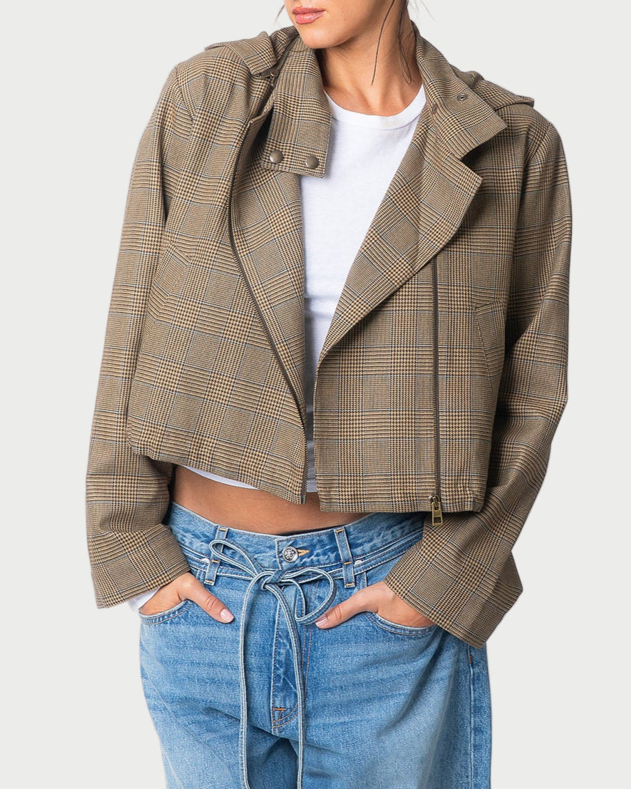 A person wears the limited edition WE-AR4 Underground Bomber Jacket in brown plaid over a white tee and loose, light blue tied-waist jeans. The upcycled cotton-blend jacket by WE-AR4 adds unique flair; their face is partially out of frame.