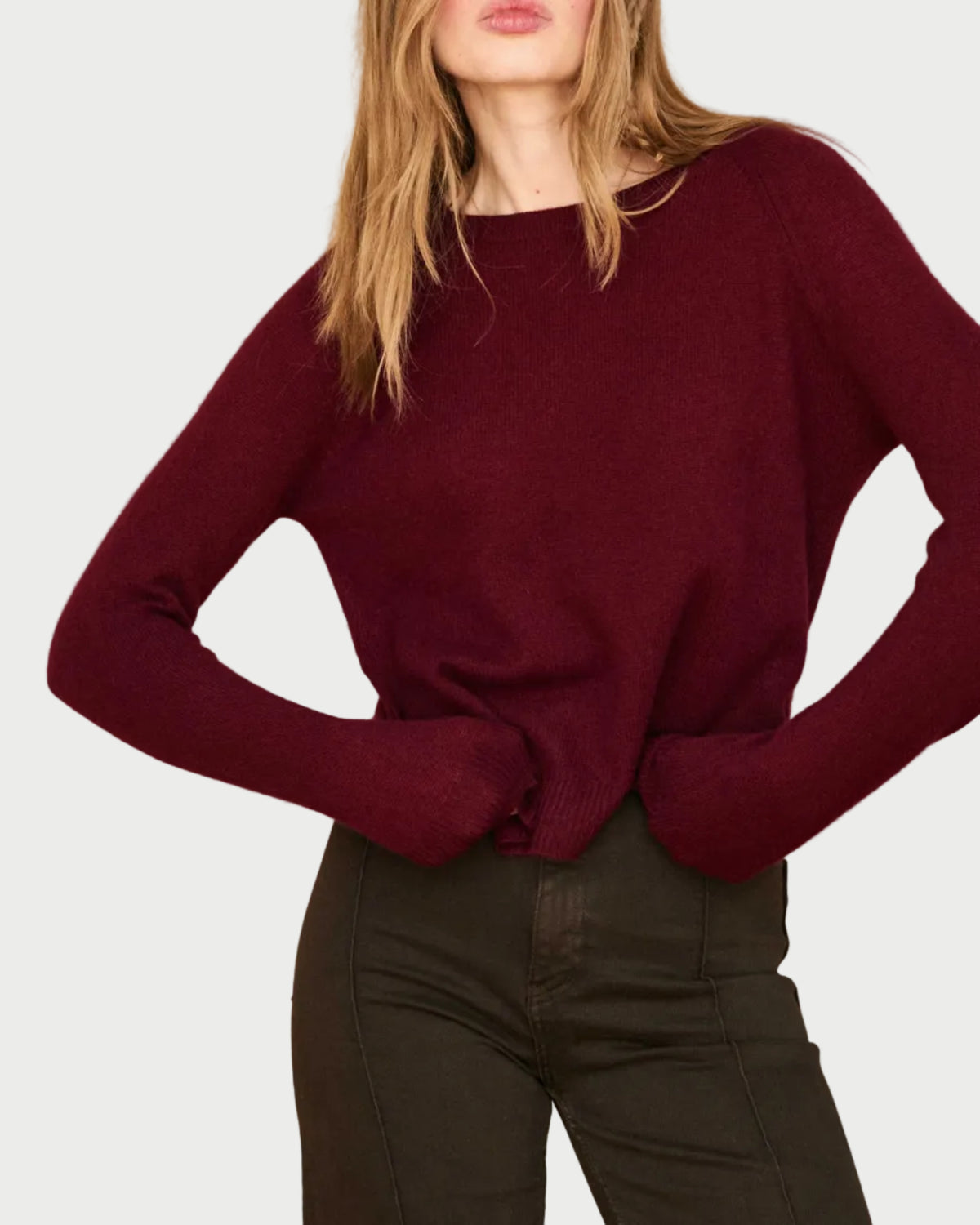 A person wearing a relaxed fit, burgundy JUMPER 1234 Distressed Cashmere Crew sweater and dark trousers.