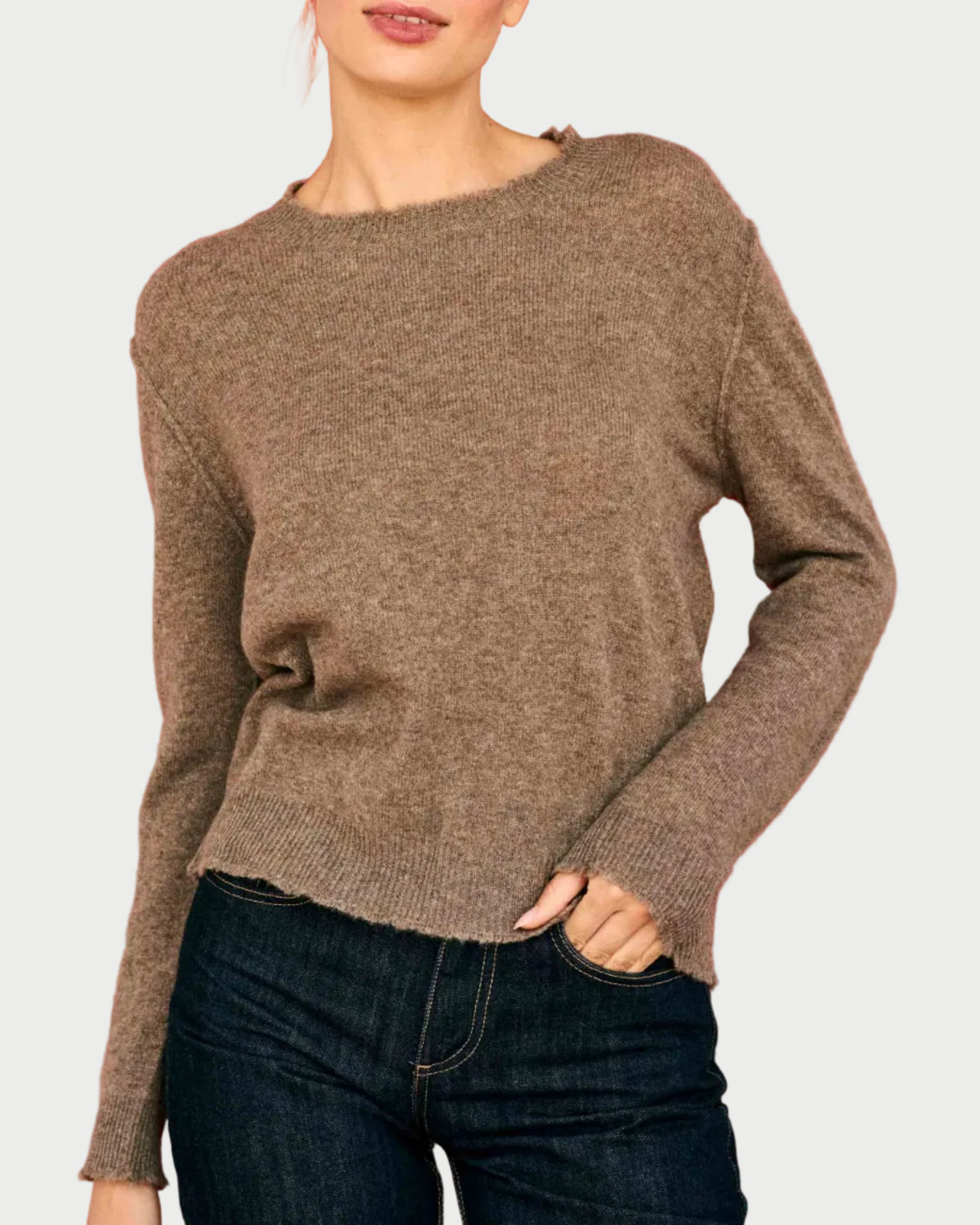 A person wearing a JUMPER 1234 Distressed Cashmere Crew Moose, a relaxed-fit, brown crew-neck sweater with distressed, raw-edge detailing at the neckline, cuffs, and hem.