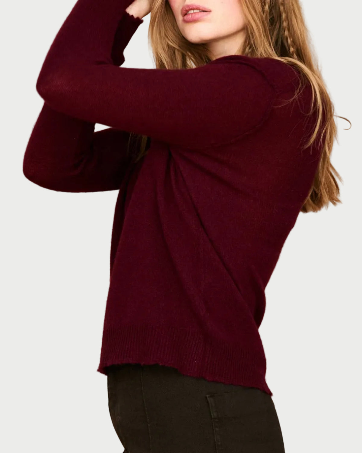 A person wearing a relaxed fit, burgundy JUMPER 1234 Distressed Cashmere Crew, a long-sleeved crewneck sweater with distressed ribbed hem detail.
