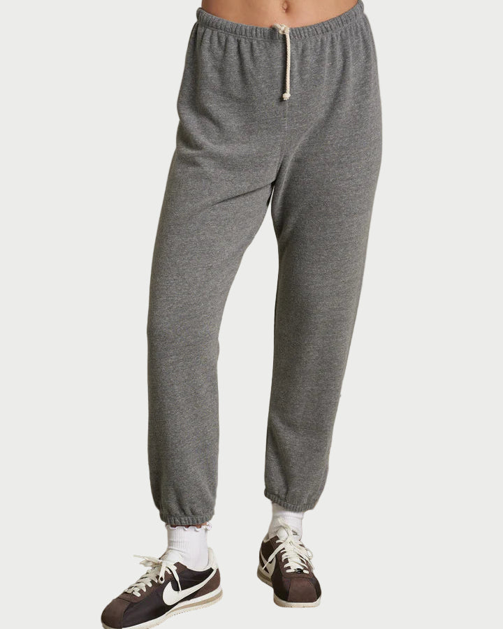 Person wearing gray sweatpants and black sneakers on a plain background