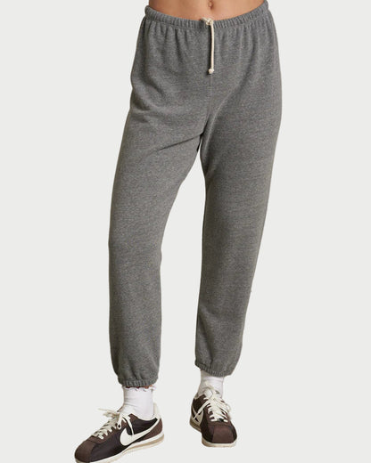 Person wearing gray sweatpants and black sneakers on a plain background