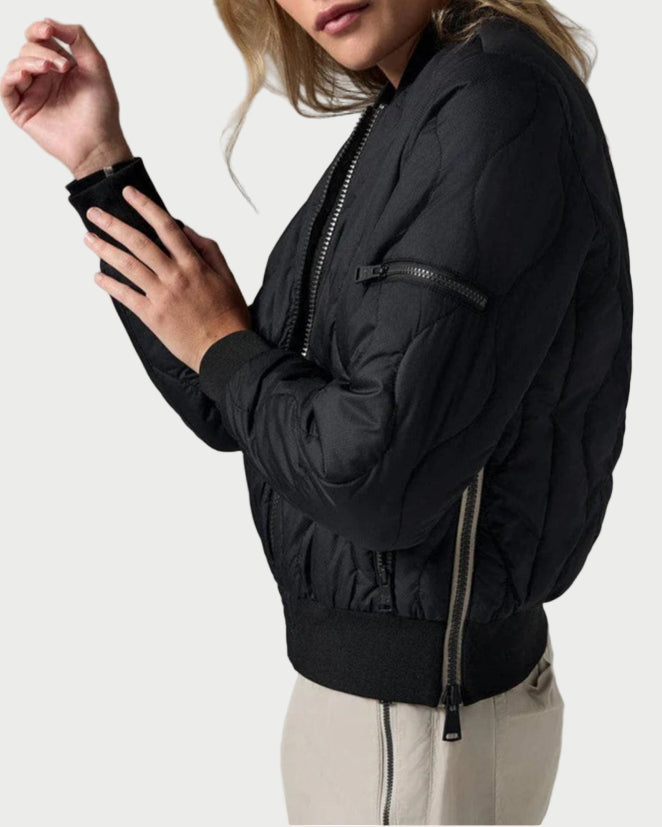 Woman wearing a black bomber jacket against a neutral background