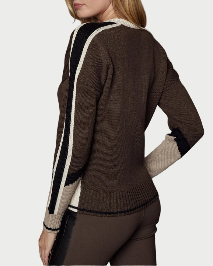 Woman wearing a brown sweater with white accents against a textured gray background