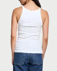 Woman wearing a white tank top and blue jeans against a plain background