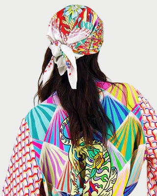 Woman wearing a colorful patterned dress with a headscarf on a white background