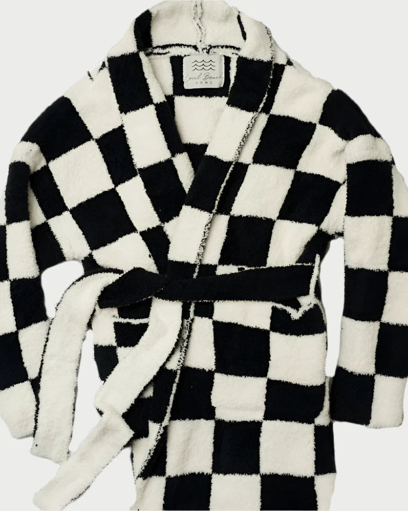 Experience comfort with the Local Beach Black Checker Luxe Robe by LOCAL BEACH—a plush microfiber robe featuring a bold black and white checkered design, long sleeves, a shawl collar, and a matching waist tie.