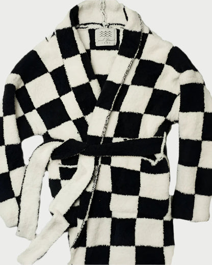 Experience comfort with the Local Beach Black Checker Luxe Robe by LOCAL BEACH—a plush microfiber robe featuring a bold black and white checkered design, long sleeves, a shawl collar, and a matching waist tie.