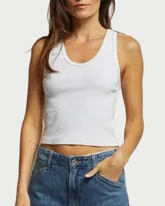 Woman wearing a white tank top and blue jeans against a plain background