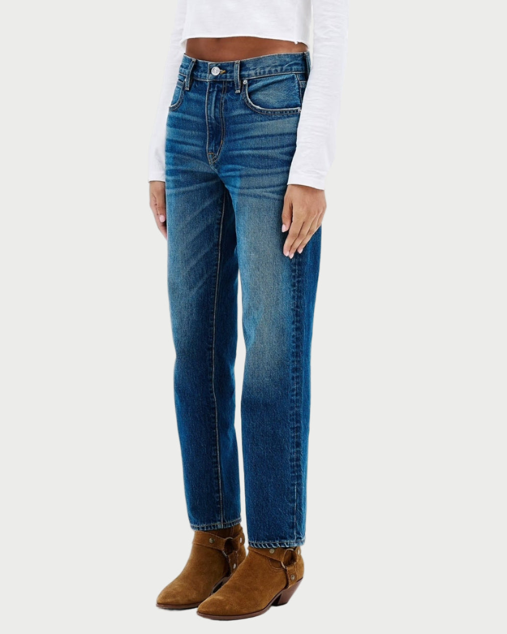 Woman wearing a white long-sleeve top and blue jeans on a white background