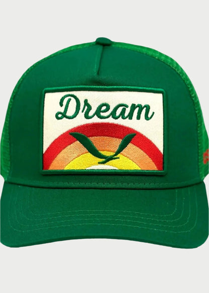 The Soulbyrd Dream Trucker Hat by Soulbyrd is green with a "Dream" patch above an embroidered rainbow sunrise and green checkmark, plus an adjustable snapback closure for the perfect fit.