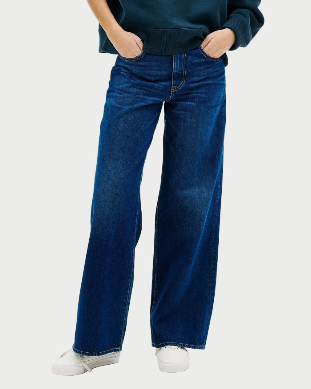 Person wearing a dark blue sweater and jeans on a white background