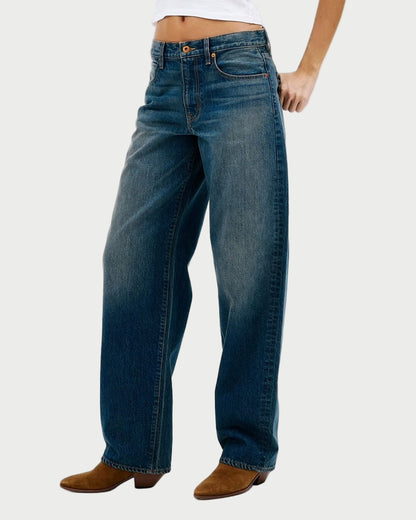 Woman wearing blue jeans and a white top on a white background