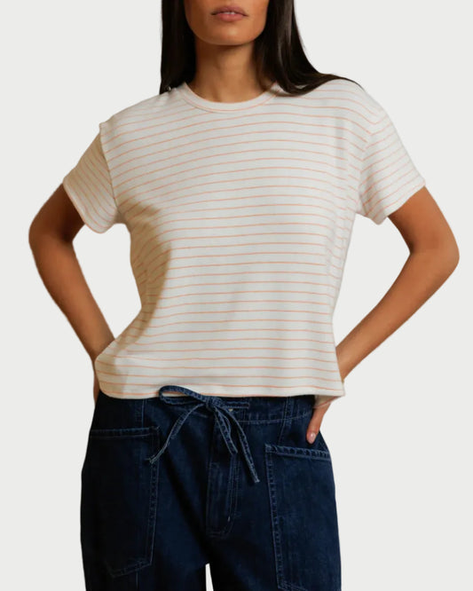 Woman wearing a white striped t-shirt and dark pants against a plain background