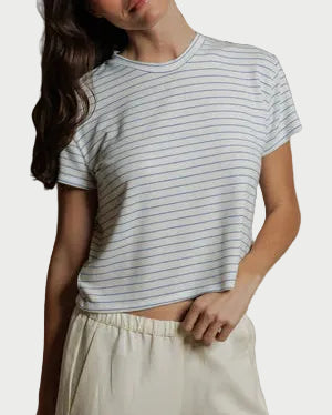 Woman wearing a striped t-shirt and white pants against a plain background