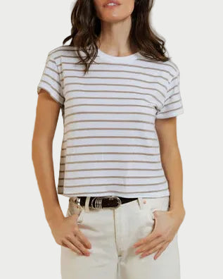 Woman wearing a striped shirt and white pants against a plain background