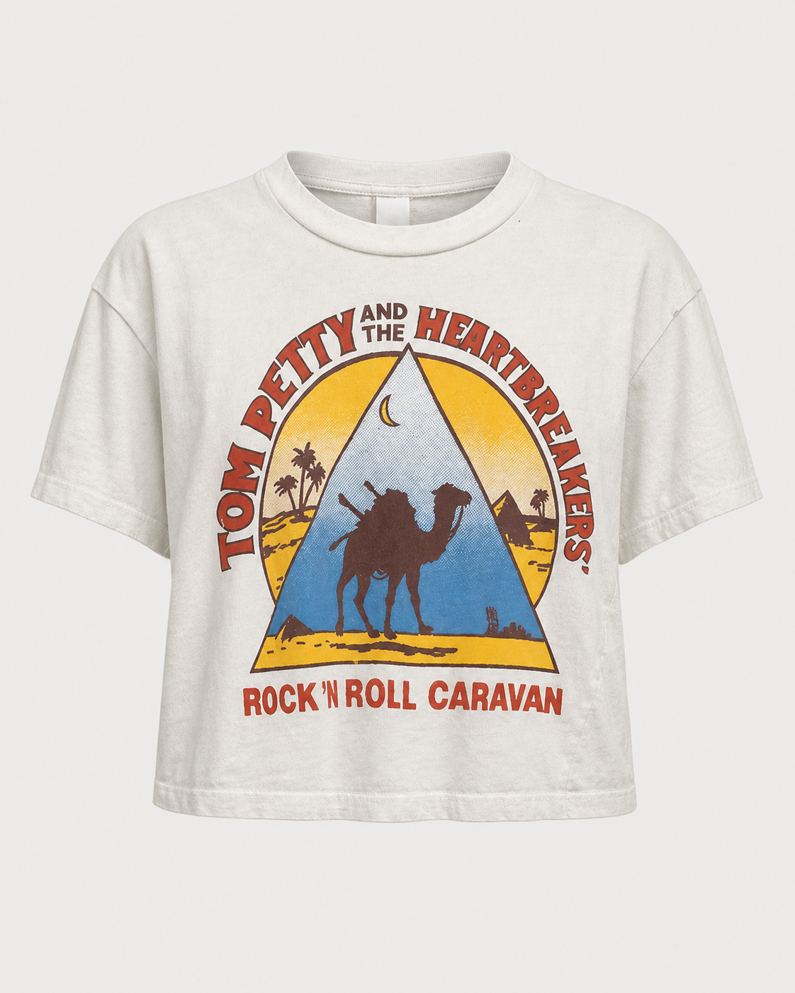 The Madeworn Tom Petty Crop Tee by Madeworn is a white cropped T-shirt featuring a striking graphic of a camel, pyramid, and crescent moon, with “Tom Petty and the Heartbreakers” and “Rock ’N Roll Caravan” printed in bold red and yellow lettering—a must-have vintage band tee for fans or anyone looking to add a standout cropped graphic tee to their collection.