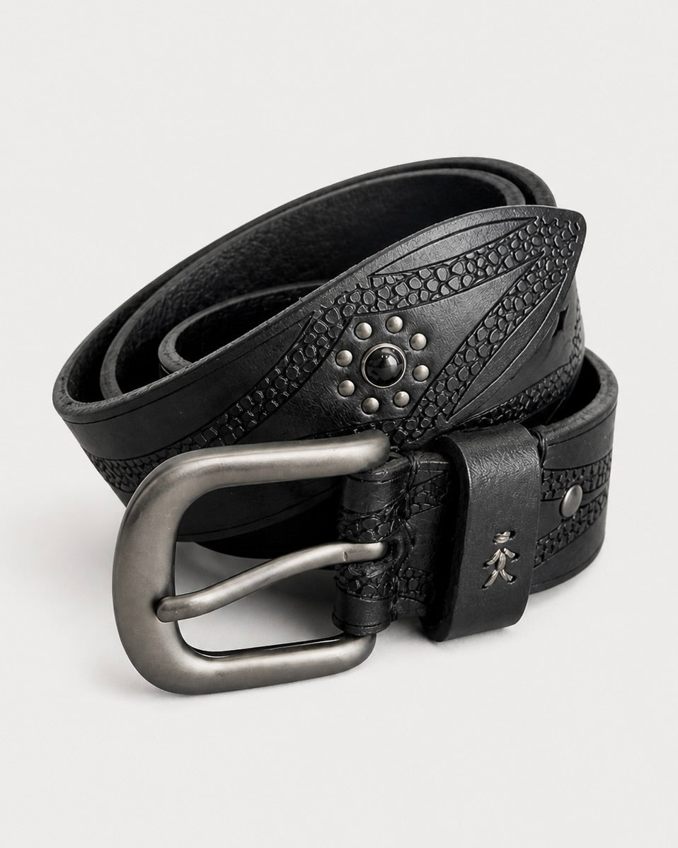The Henry Beguelin Church Belt—a black leather accessory adorned with textured patterns, metal studs, and a silver buckle—showcases the brand’s artisanal craftsmanship as it rests gracefully coiled on a light background.