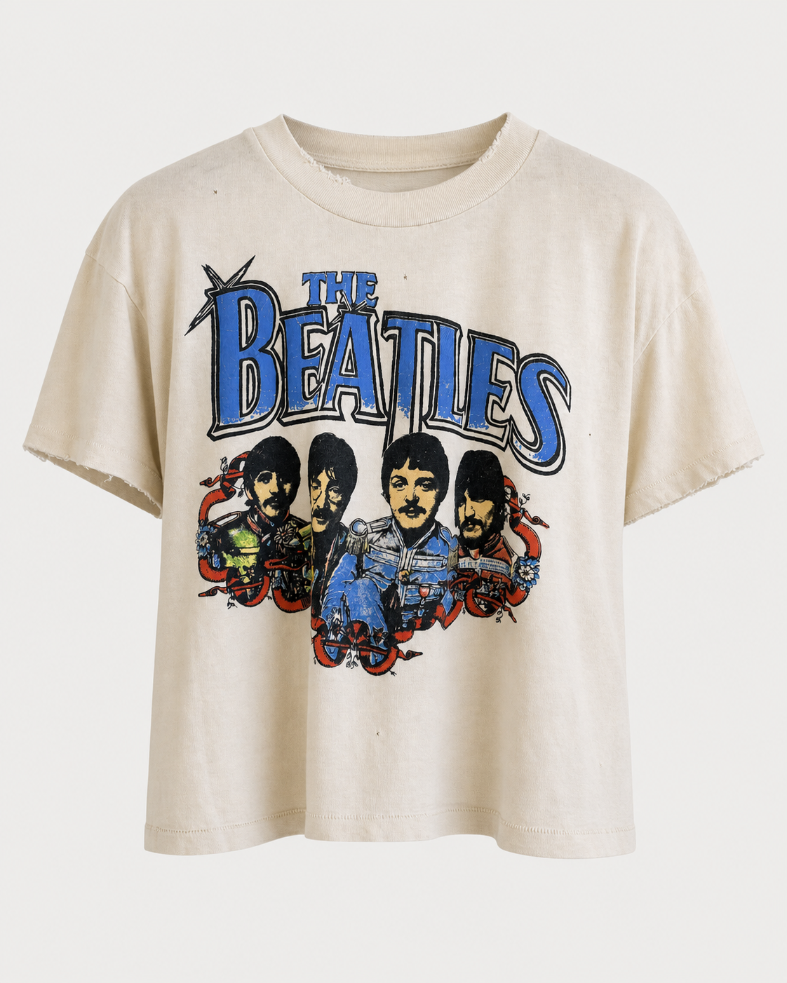 The Madeworn The Beatles Crop Tee by Madeworn is a beige, vintage-inspired band T-shirt handmade in Los Angeles, showcasing colorful cartoon-style illustrations of The Beatles and their name in bold blue letters across the chest.
