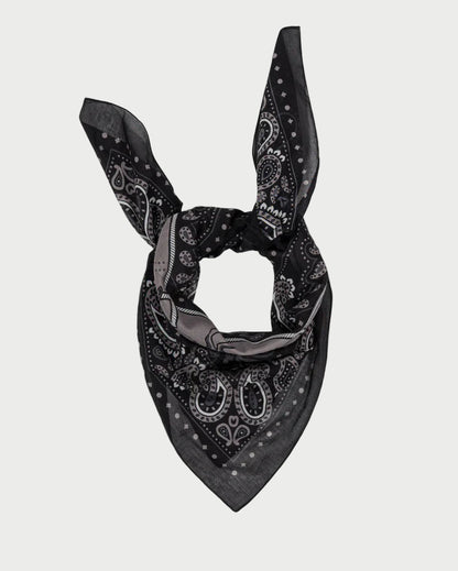 The Rodeo Scarf by Maison Lecomte Flament is a black cotton voile bandana with a classic white and gray pattern, worn knotted with pointed tips up and a triangular end down.
