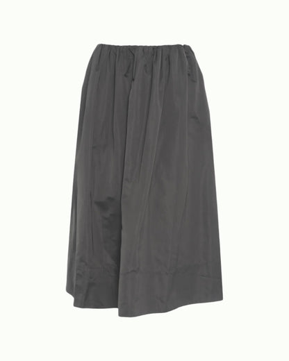 The Miss Skirt by Herskind is a loose-fitting, dark gray midi skirt featuring an elastic waistband, slightly flared silhouette, and lightweight, subtly shiny fabric for effortless style.