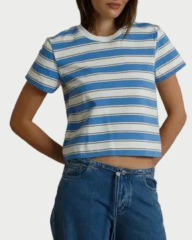 Person wearing a blue and white striped shirt and blue jeans against a beige background