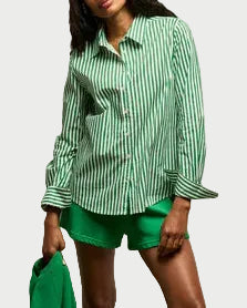 A woman wears the perfectwhitetee Gisele Button Down in green and white stripes with bright green shorts, holding a matching jacket—her look finished with this signature style from perfectwhitetee.