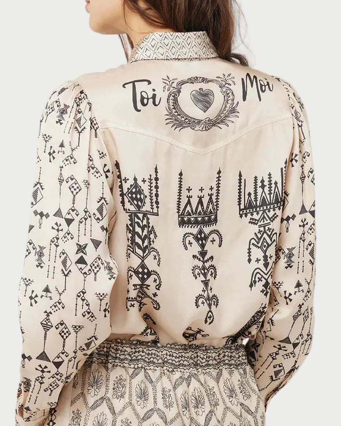 Woman wearing a sheer blouse with black patterns on a white background