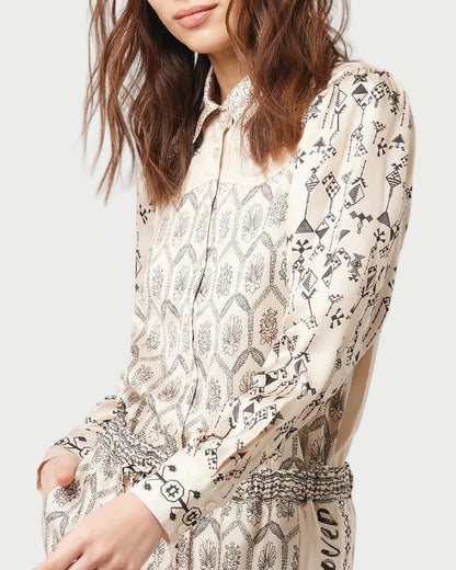 Woman wearing a patterned blouse against a plain background