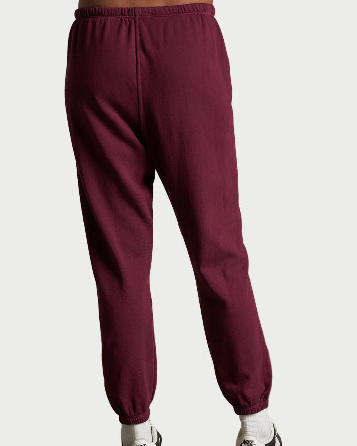 Maroon sweatpants worn by a person on a plain background