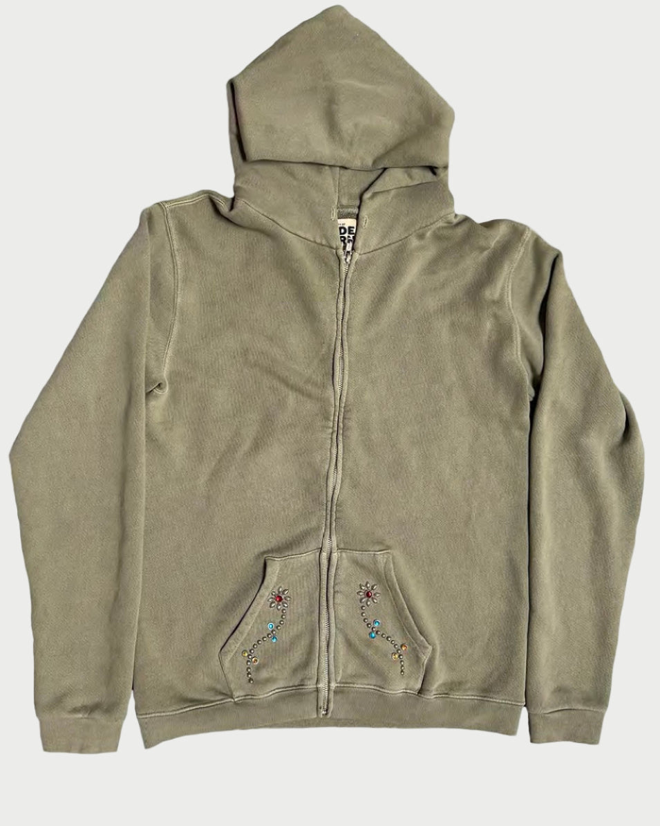The Madeworn Flower Power Hoodie by Madeworn features an olive green zip-up design, hood, front pockets, colorful embroidered designs, and rhinestone floral accents on the pockets. Displayed flat on a white background for retro athleisure style.