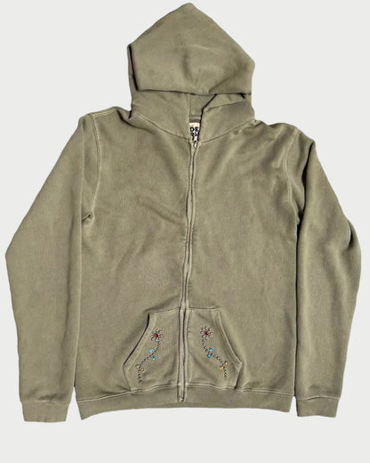 The Madeworn Flower Power Hoodie by Madeworn features an olive green zip-up design, hood, front pockets, colorful embroidered designs, and rhinestone floral accents on the pockets. Displayed flat on a white background for retro athleisure style.