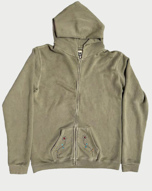 The Madeworn Flower Power Hoodie by Madeworn features an olive green zip-up design, hood, front pockets, colorful embroidered designs, and rhinestone floral accents on the pockets. Displayed flat on a white background for retro athleisure style.