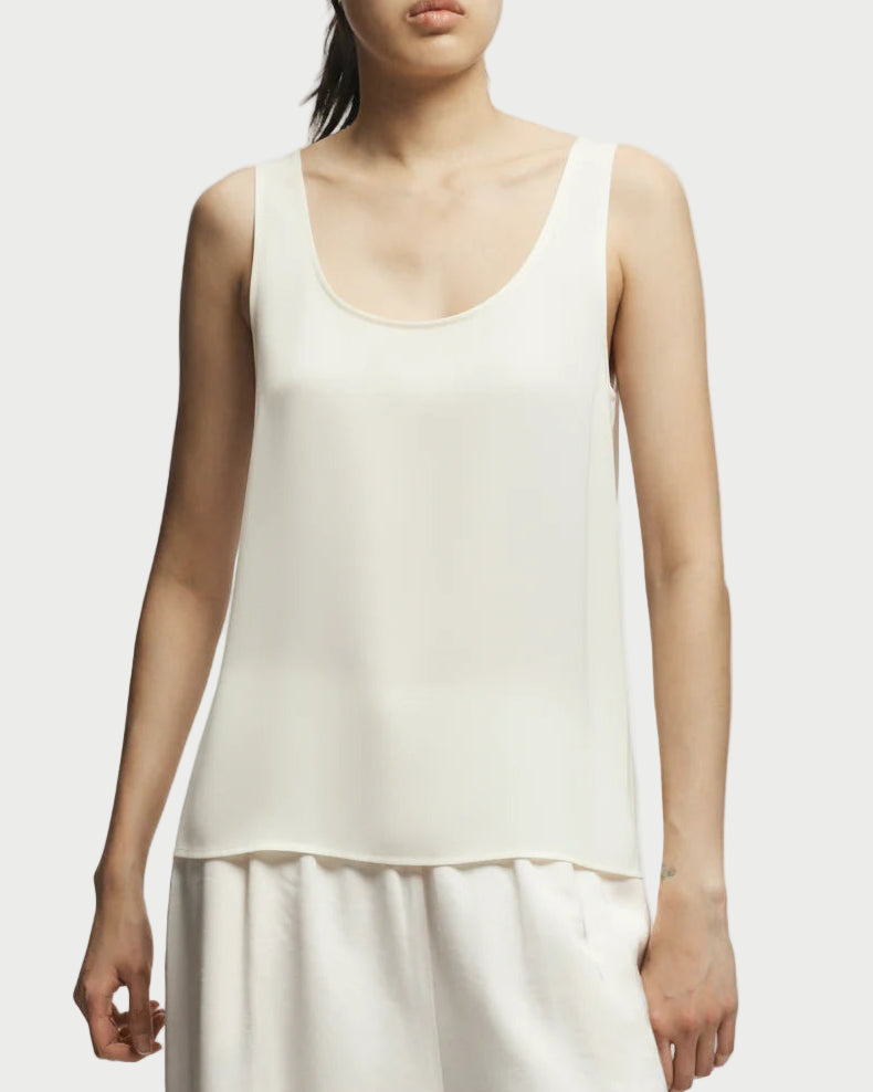 A person models the Saint Art Isola Ivory Scoop Neck Tank by Saint Art NY with matching white pants against a plain light background—a true minimalist essential.