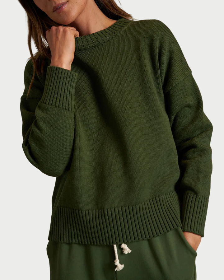 A person wears the perfectwhitetee Green Janet Sweater, a loose boxy-fit sweater with ribbed cuffs and hem, paired with matching green pants with a white drawstring, standing against a plain light background.