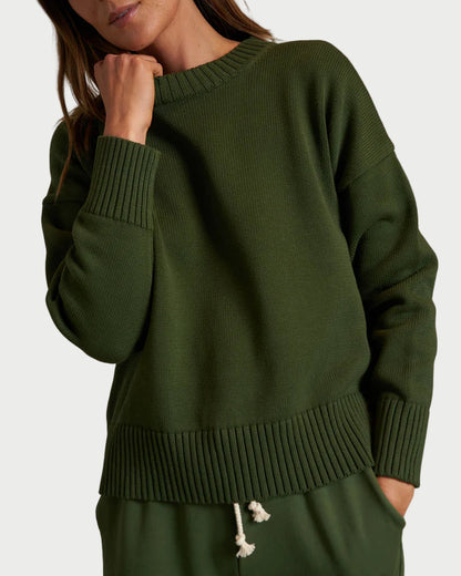A person wears the perfectwhitetee Green Janet Sweater, a loose boxy-fit sweater with ribbed cuffs and hem, paired with matching green pants with a white drawstring, standing against a plain light background.