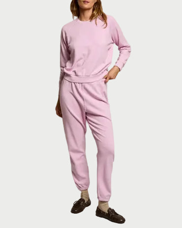 Person wearing a pink tracksuit against a plain background