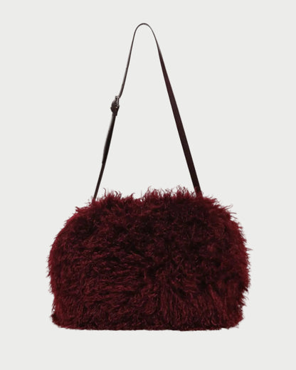 A dark burgundy shaggy faux-fur shoulder bag with a slim black strap, shown against a plain light gray background.